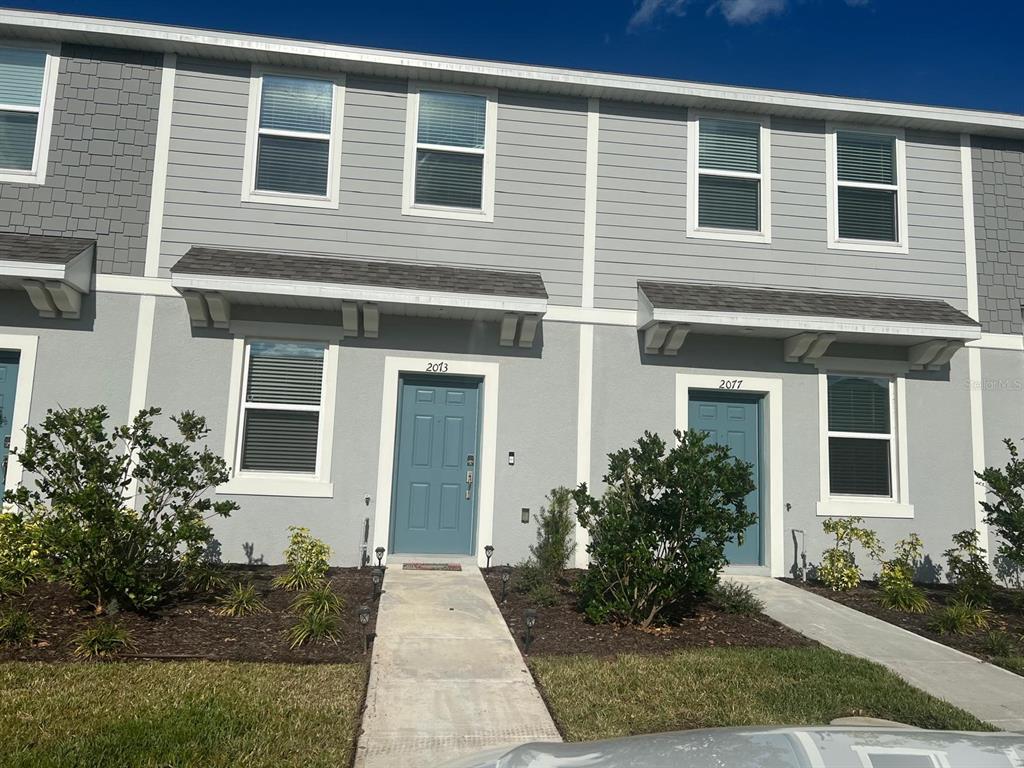 A two-story gray townhouse exterior with blue doors and small front walkways — 2073 VIEWFINDER STREET, KISSIMMEE, FL