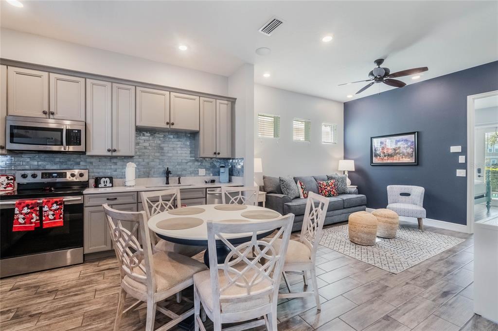 A kitchen with grey cabinets and a dining area adjacent to a living room — 8008 SANDY TOES WAY, KISSIMMEE, FL