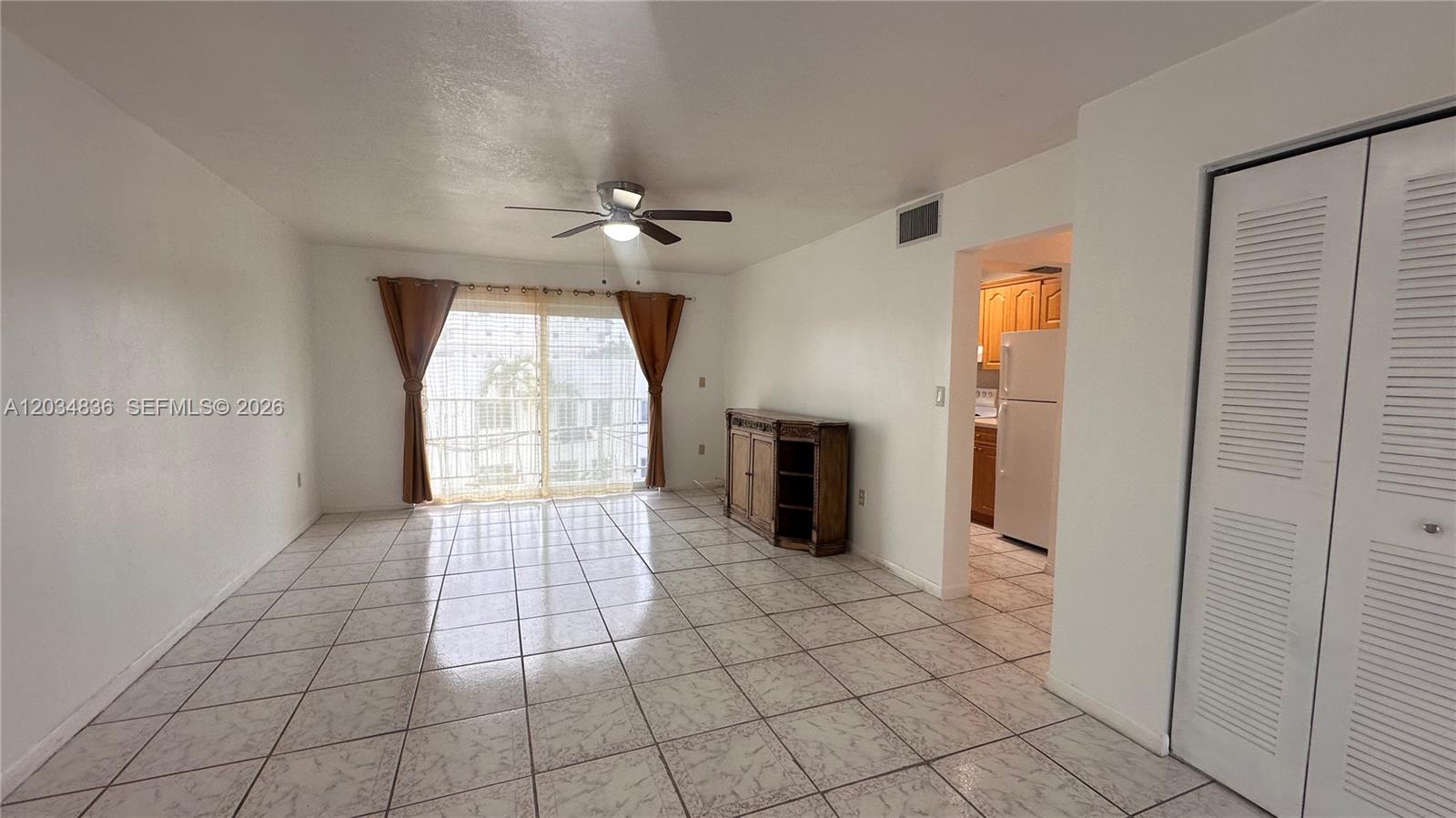 A living room with tiled floors, a ceiling fan, and a sliding glass door — MIAMI BEACH, FL