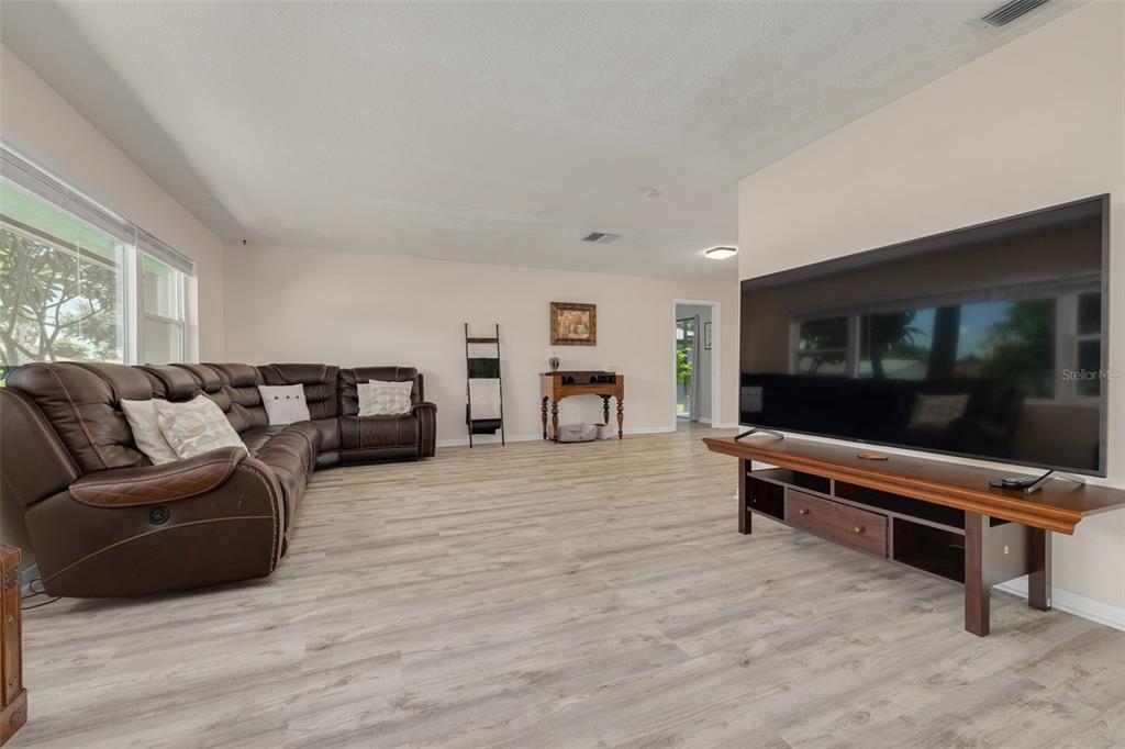 A living room features light wood-look flooring, a large brown sectional sofa, and a television — 8960 140TH STREET, SEMINOLE, FL