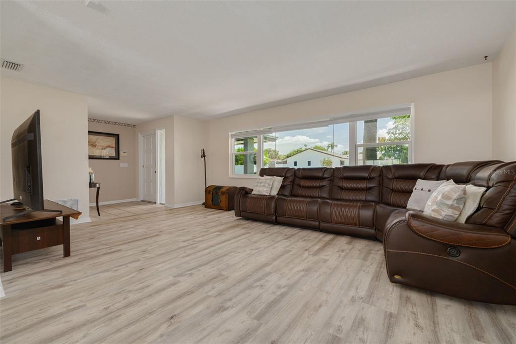 A living room features light wood-look flooring, a large brown sectional sofa, and a television — 8960 140TH STREET, SEMINOLE, FL