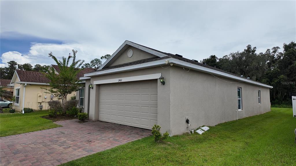A beige, single-story house with a two-car garage and a brick paver driveway — 2462 ADDISON CREEK DRIVE, KISSIMMEE, FL