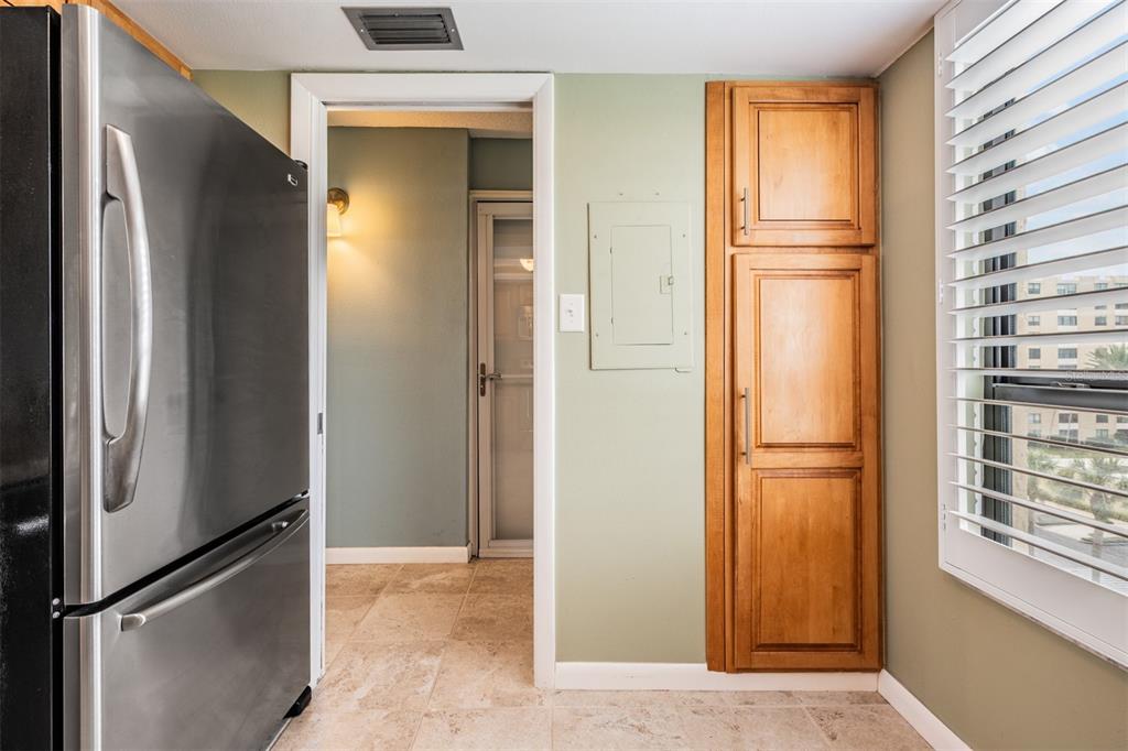 A kitchen features a stainless steel refrigerator, a wooden pantry cabinet, and a doorway — 2620 COVE CAY DRIVE UNIT 601, CLEARWATER, FL