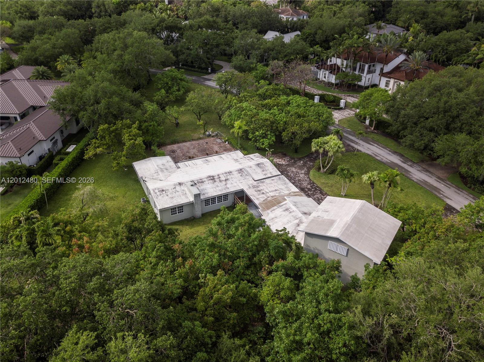 An aerial view shows a single-story house with a flat roof surrounded by dense trees — 10851 SW 68th Ave, Pinecrest FL 33156, PINECREST, FL