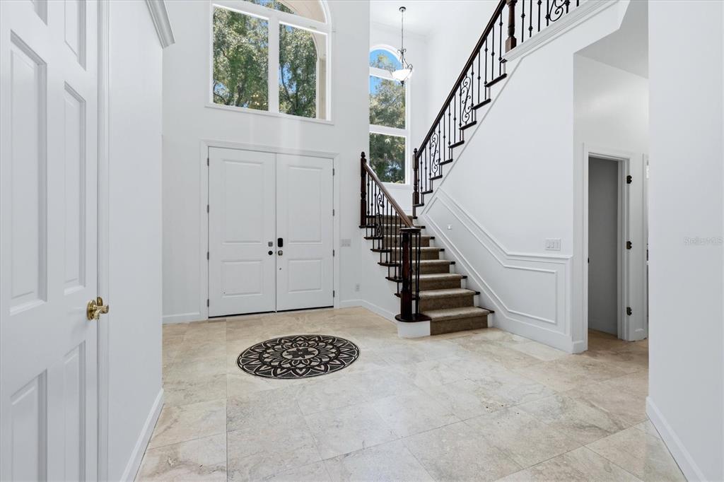 A bright foyer features a grand staircase, tile flooring, and double front doors — 1351 DIXIE LEE LANE, SARASOTA, FL