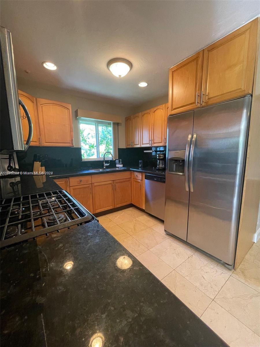 A kitchen features light wood cabinets, black countertops, stainless steel appliances, and tile flooring — 1531 Moffett St, Hollywood FL 33020, HOLLYWOOD, FL
