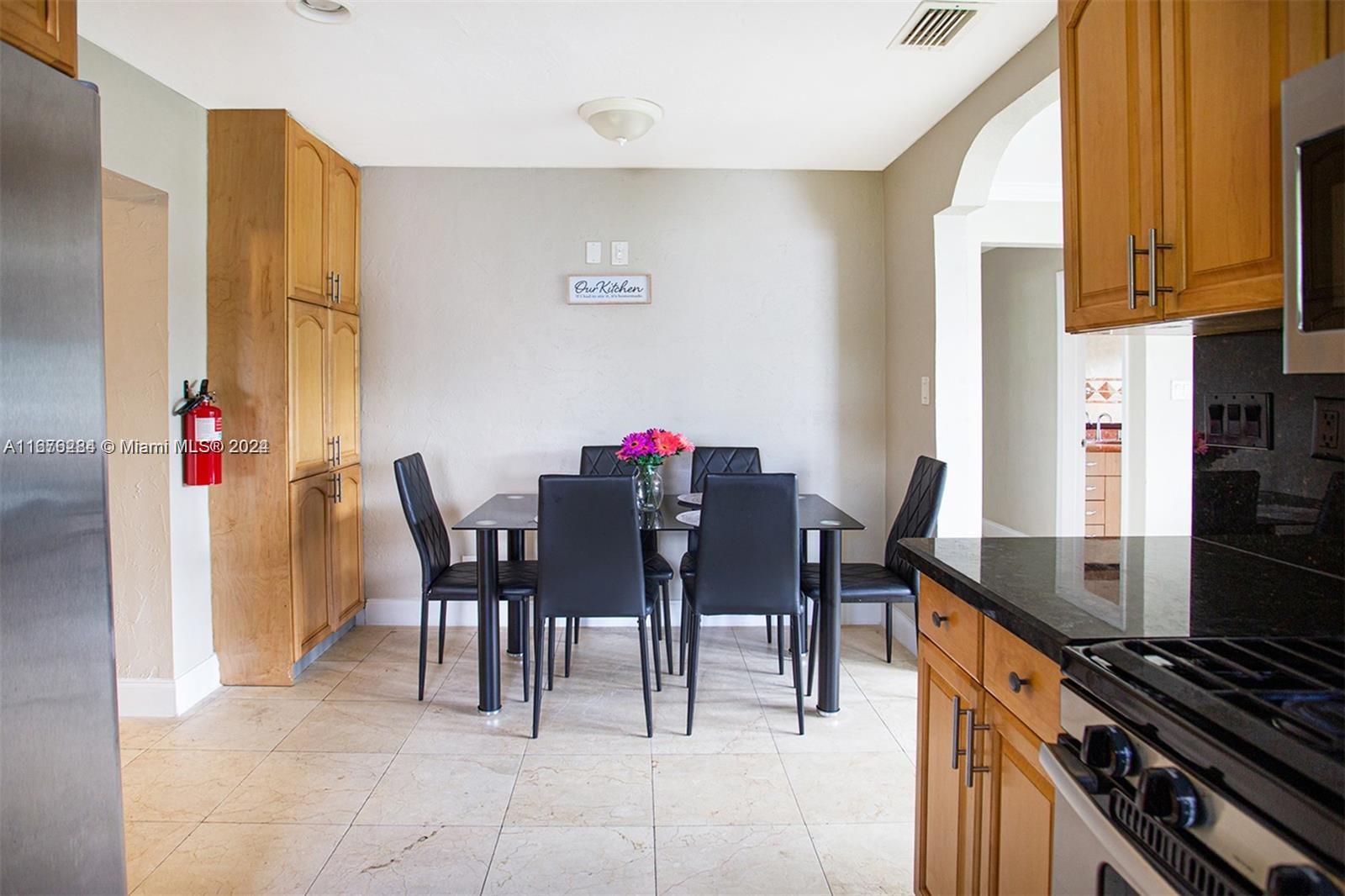 A dining area features a glass table with six black chairs and light tile flooring — 1531 Moffett St, Hollywood FL 33020, HOLLYWOOD, FL