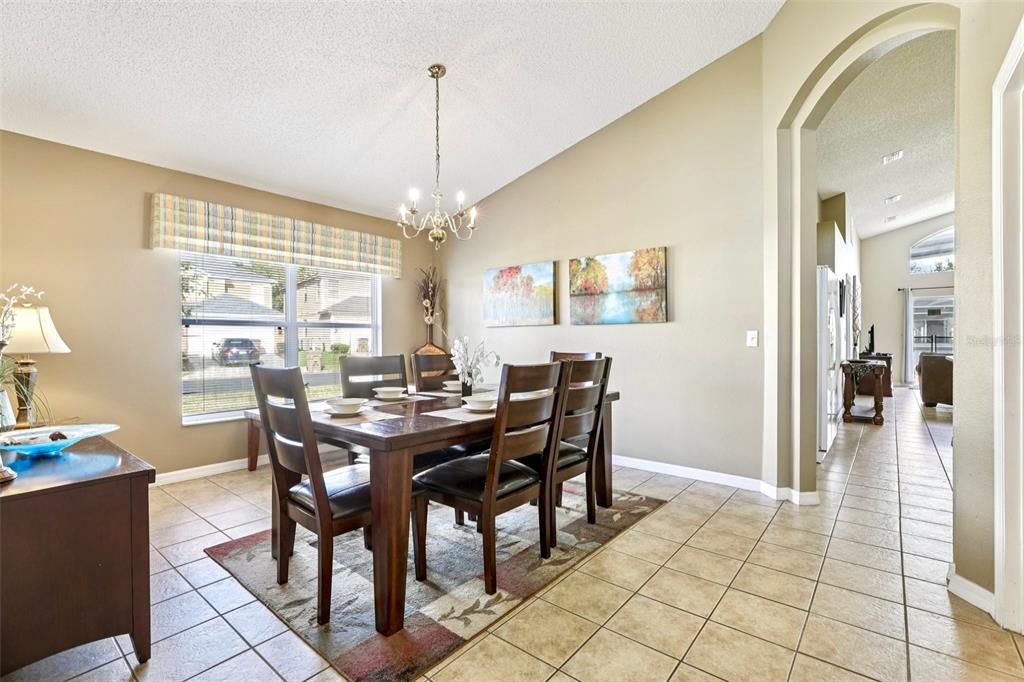 A dining room with a wooden table, six chairs, tile flooring, and a chandelier — 151 HIDEAWAY BEACH LANE, KISSIMMEE, FL