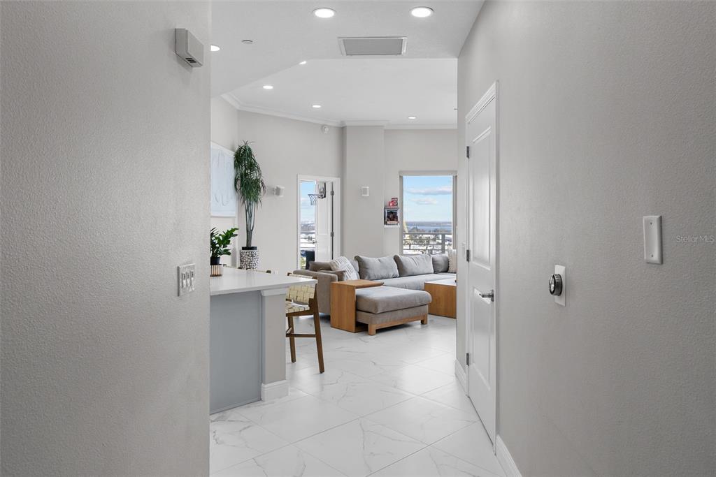 A hallway leads into a bright living area with white tile floors and a balcony — 449 S 12TH STREET UNIT 1402, TAMPA, FL
