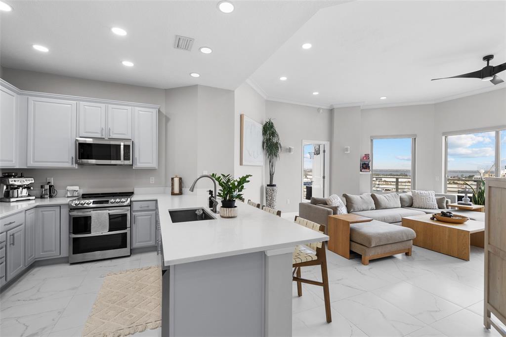 A modern kitchen with white cabinets and a central island opens into a living area — 449 S 12TH STREET UNIT 1402, TAMPA, FL