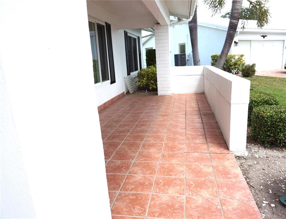 A covered patio features terracotta-colored tile flooring and a low white masonry wall — 4031 93RD TERRACE N UNIT 5, PINELLAS PARK, FL