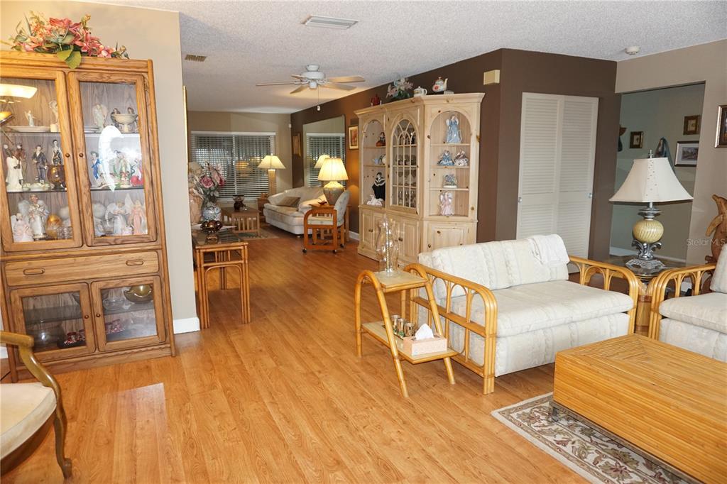 A living room with light wood flooring, two large display cabinets, and rattan furniture — 4031 93RD TERRACE N UNIT 5, PINELLAS PARK, FL