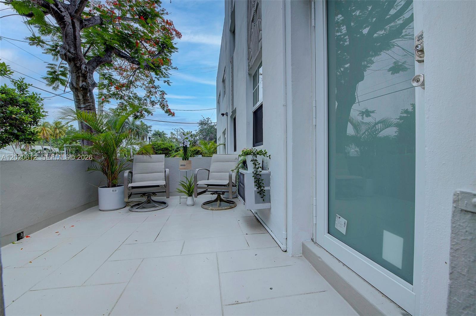 An outdoor balcony features two chairs, potted plants, and a wall-mounted air conditioning unit — 2463 Pine Tree Dr # 3, Miami Beach FL 33140, MIAMI BEACH, FL