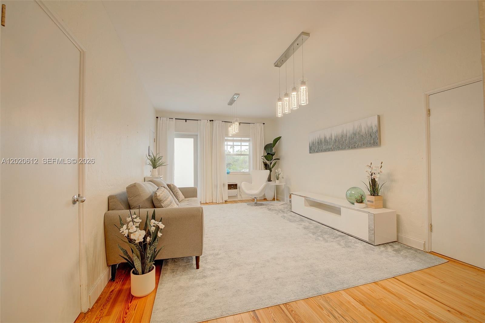 A living room features a gray sofa, a white media console, and a large rug — 2463 Pine Tree Dr # 3, Miami Beach FL 33140, MIAMI BEACH, FL