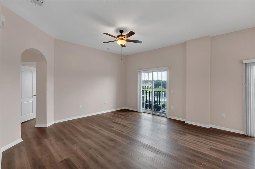 An empty room with wood-look flooring, a ceiling fan, and sliding glass doors to a balcony — 1913 ESTANCIA CIRCLE UNIT 1913, KISSIMMEE, FL