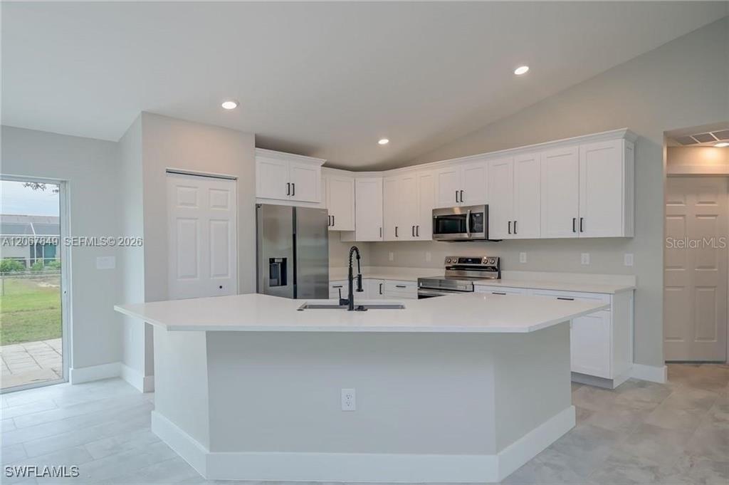 A modern kitchen features white cabinets, stainless steel appliances, and a large central island — 204 EL DORADO BLVD N, CAPE CORAL, FL