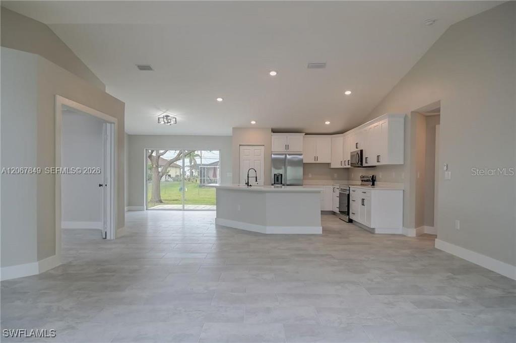A kitchen with white cabinets and a central island opens to a living area — 204 EL DORADO BLVD N, CAPE CORAL, FL