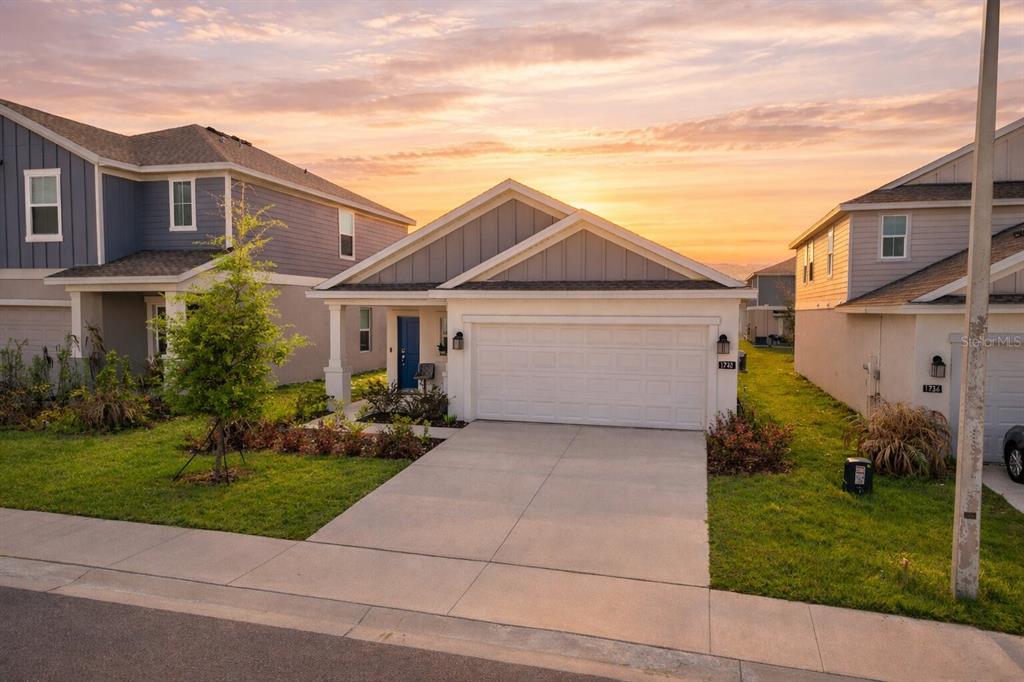 A single-story house with a white garage and blue front door at sunset — 1740 WHITE WATER COURT, DAVENPORT, FL