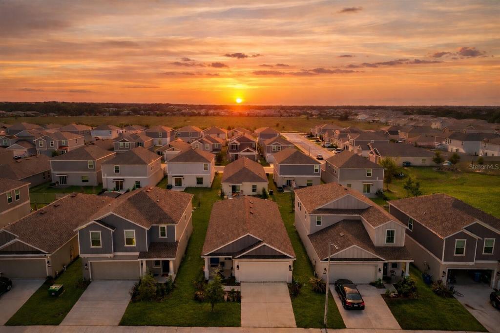 An aerial view of a suburban neighborhood at sunset with rows of single-family homes — 1740 WHITE WATER COURT, DAVENPORT, FL