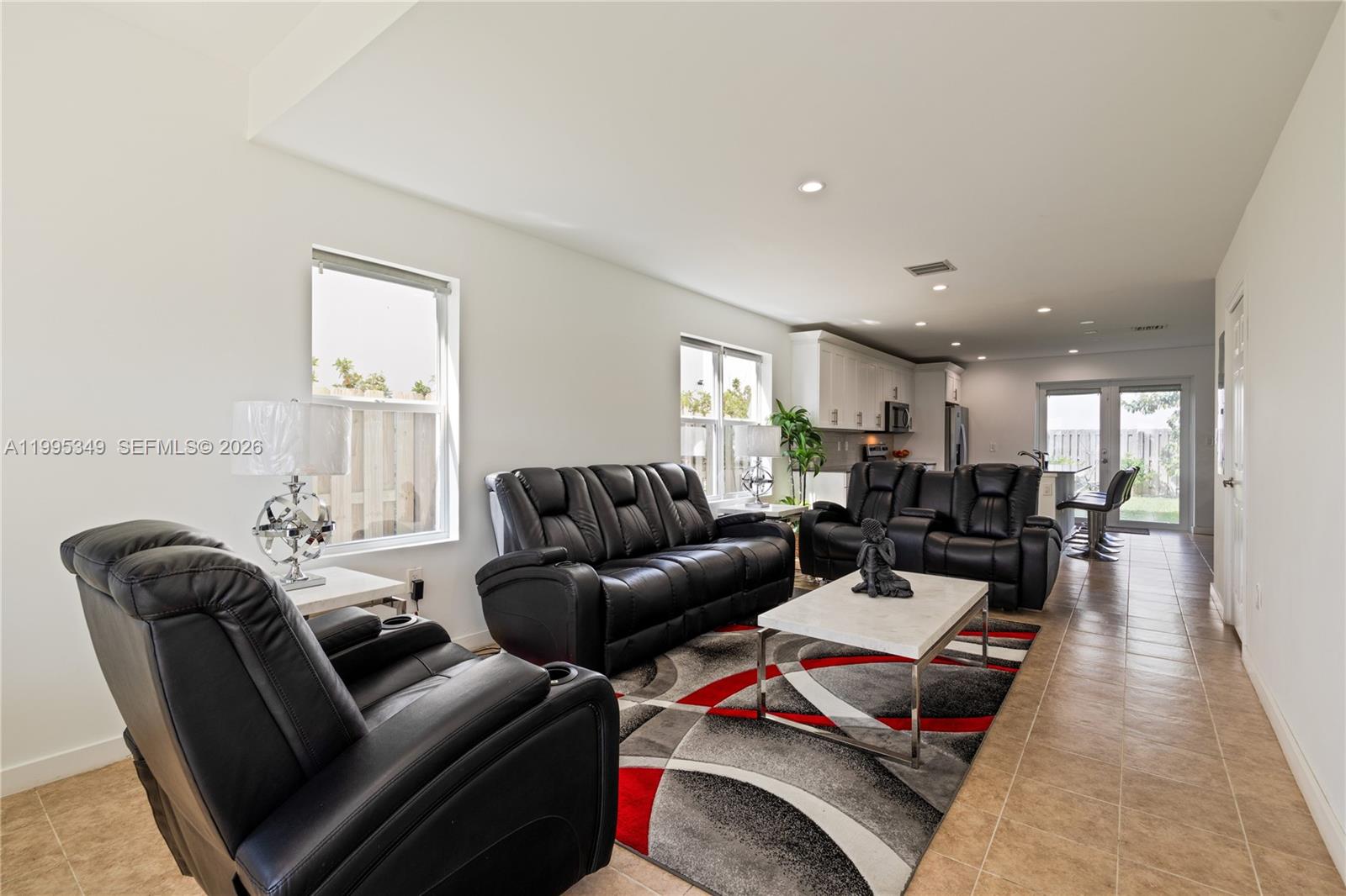 A living room features black leather furniture, a patterned rug, and an open-concept kitchen — 17970 SW 105th Ave, Miami FL 33157, MIAMI, FL