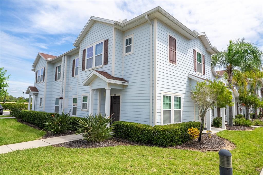 A two-story light blue residential building with brown shutters and a small front porch — 9008 SHINE DRIVE, KISSIMMEE, FL