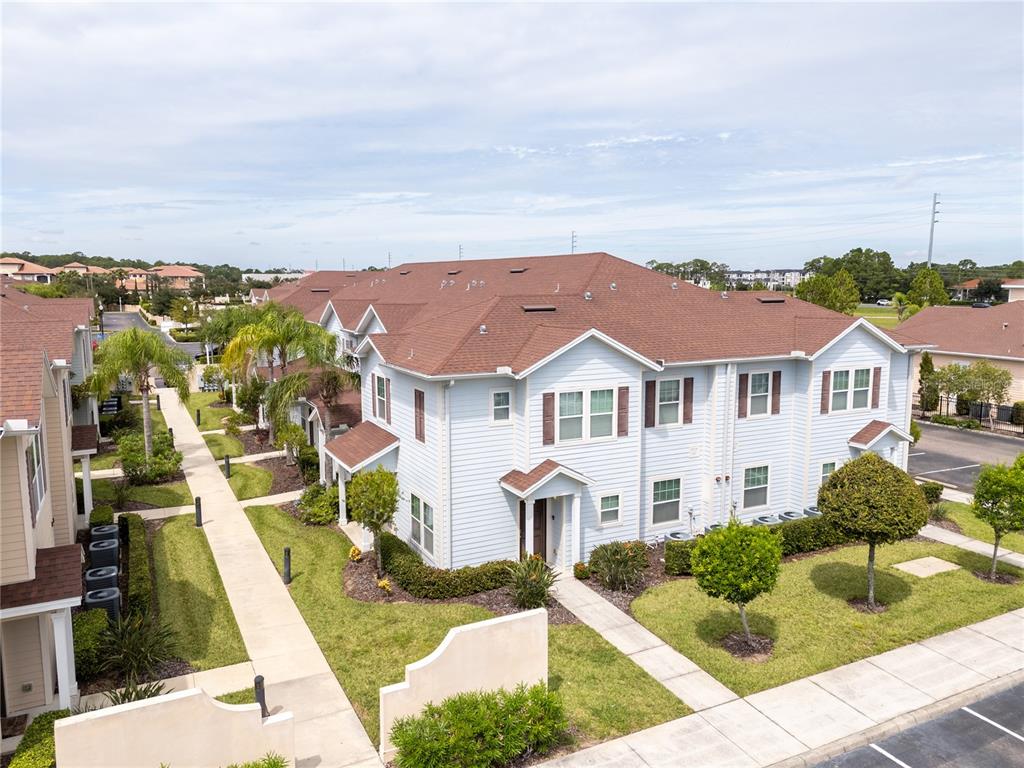 An aerial view of a light blue multi-unit townhouse building with a brown shingled roof — 9008 SHINE DRIVE, KISSIMMEE, FL