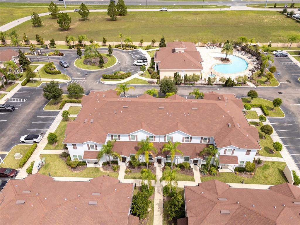 An aerial view shows a multi-unit residential building with a brown roof and pool — 9008 SHINE DRIVE, KISSIMMEE, FL