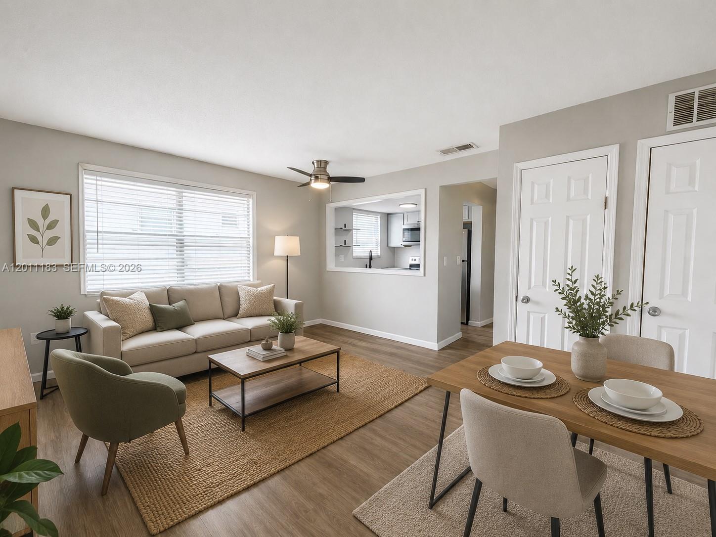 A living room and dining area feature light wood floors, neutral furniture, and a kitchen pass-through — 1208 S Ridgewood Ave, Daytona FL 32114, DAYTONA, FL