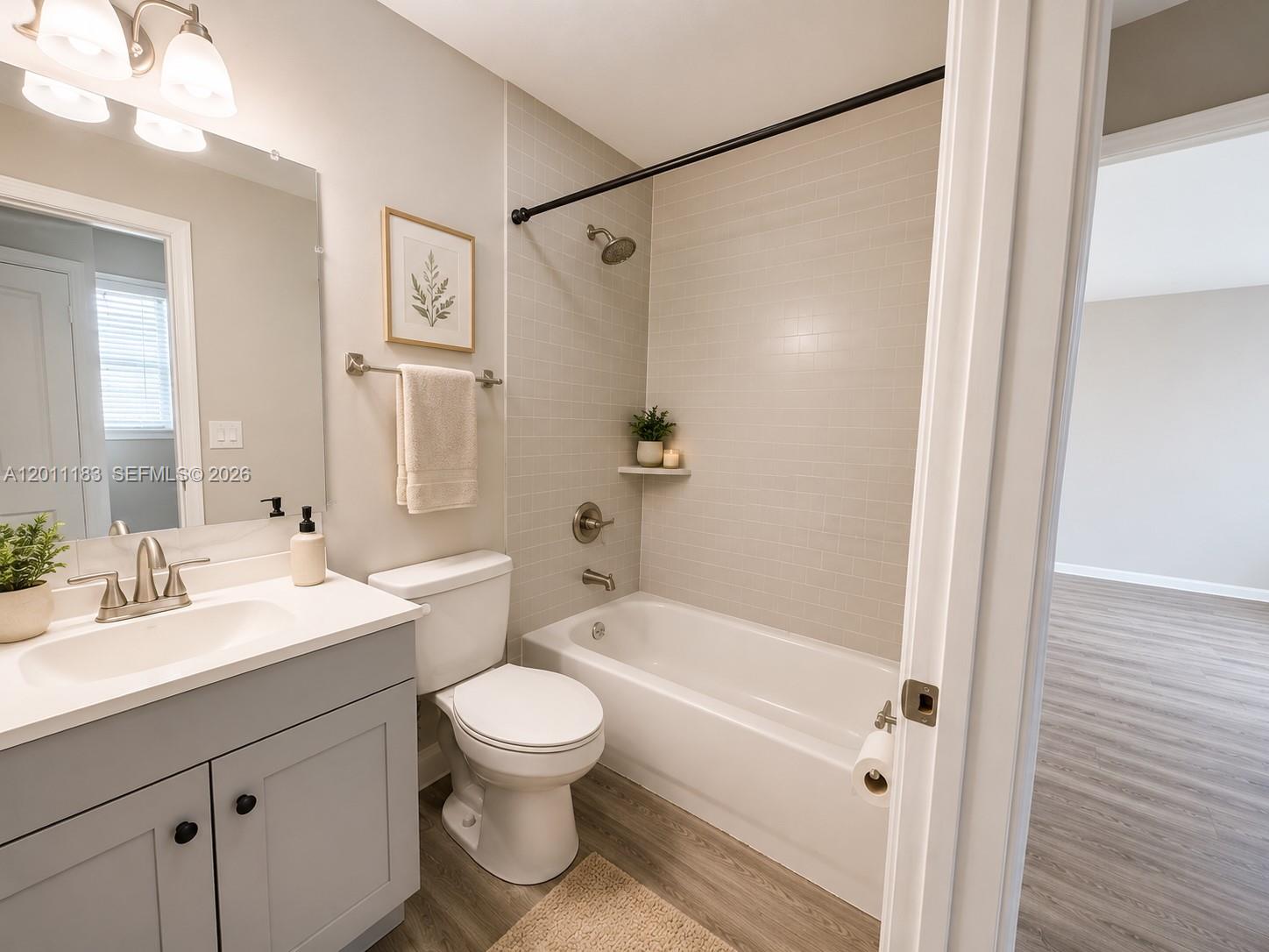 A bathroom features a gray vanity, a white toilet, and a tiled tub-shower combination — 1208 S Ridgewood Ave, Daytona FL 32114, DAYTONA, FL