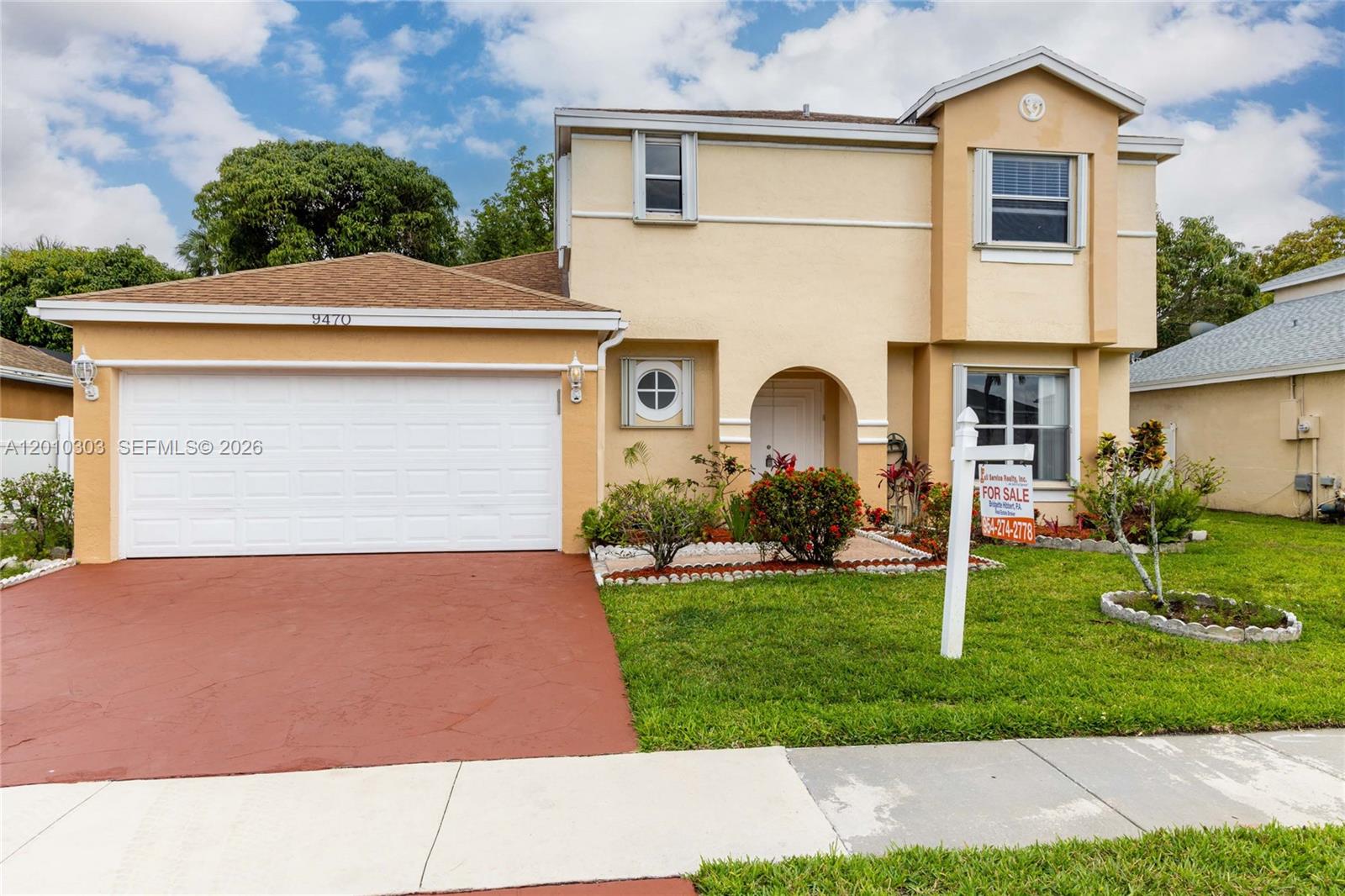 A two-story house with a tan stucco exterior, a garage, and a front lawn — 9470 Atlantic St, Miramar FL 33025, MIRAMAR, FL