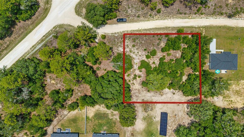 An aerial view shows a rectangular, wooded vacant lot outlined in red next to houses — 2499 SW 143RD COURT, OCALA, FL