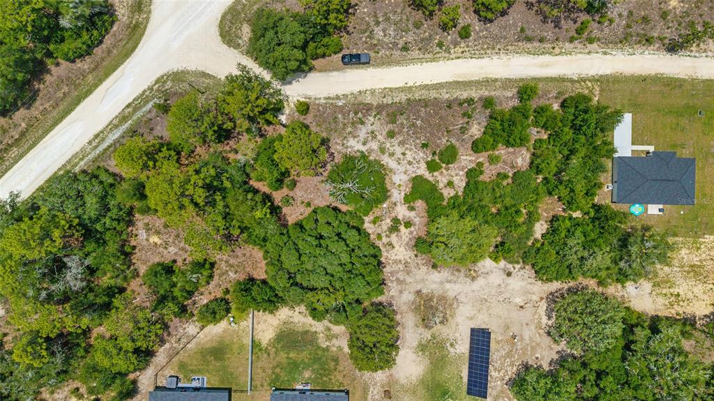 An aerial view shows a wooded residential lot with a house, solar panels, and driveway — 2499 SW 143RD COURT, OCALA, FL