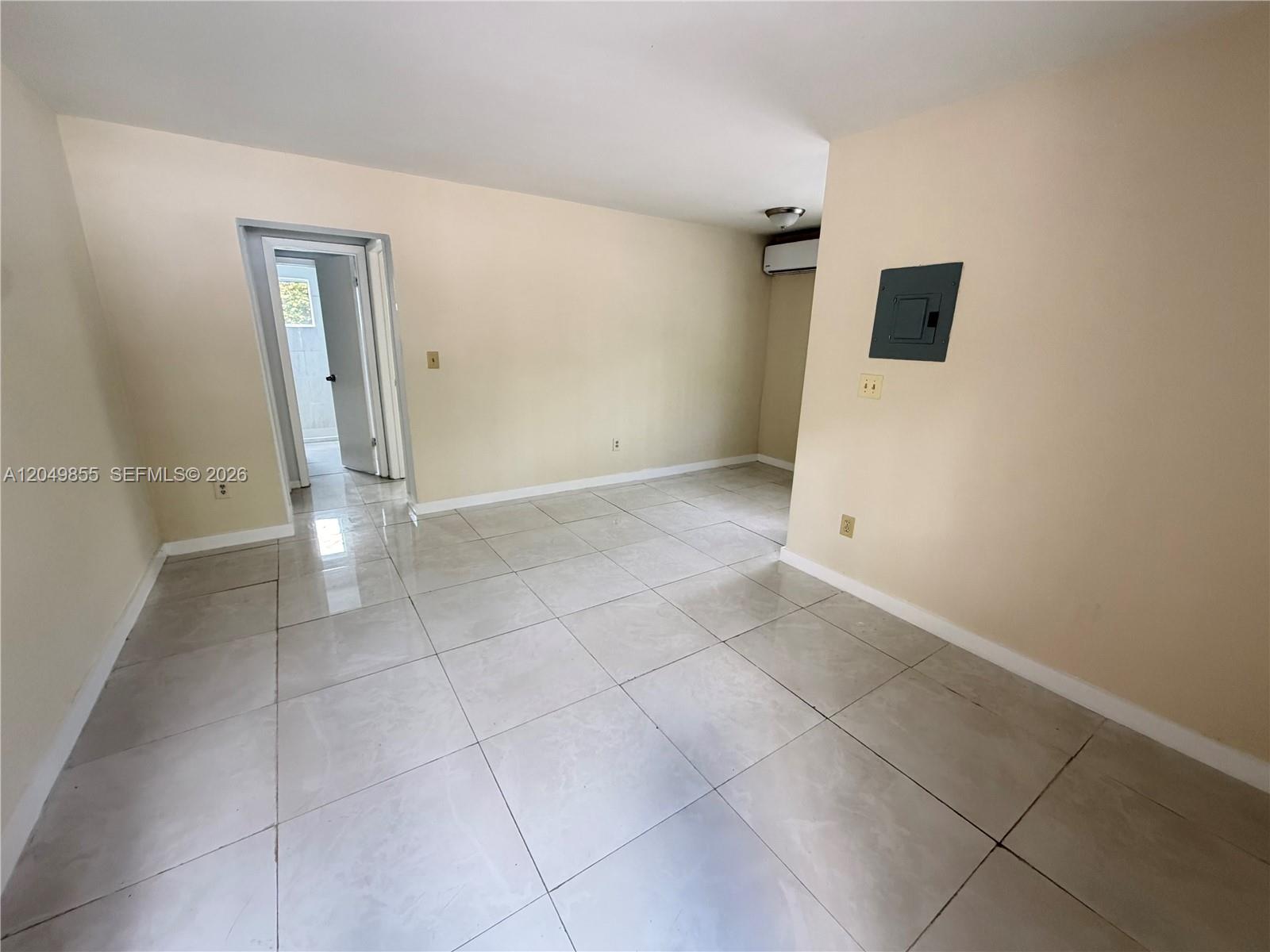 An empty room features light-colored tile flooring, beige walls, and a wall-mounted electrical panel — 1194 NW 19th Ave # 1, Miami FL 33125, MIAMI, FL