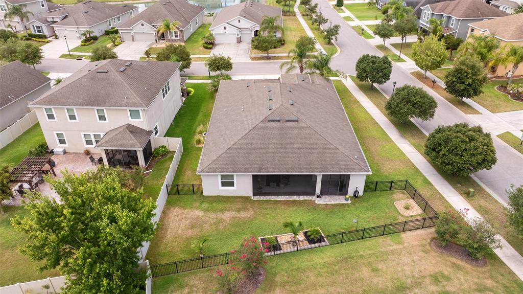 An aerial view shows the backyards and roofs of several suburban houses with fenced lawns — 32373 BANNACK LANE, WESLEY CHAPEL, FL