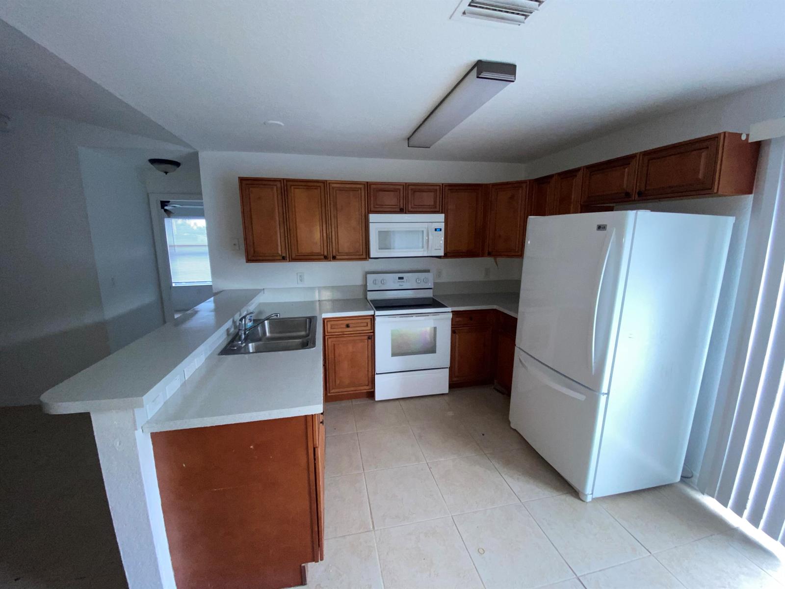 A kitchen with wood cabinets, white appliances, tile flooring, and a breakfast bar — 618 NE 1st Street # B, Boynton Beach FL 33435, BOYNTON BEACH, FL