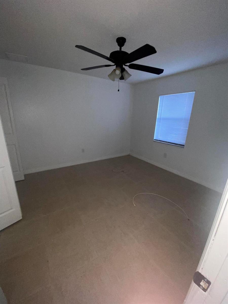 An empty bedroom features beige carpeting, white walls, and a black ceiling fan — 618 NE 1st Street # B, Boynton Beach FL 33435, BOYNTON BEACH, FL