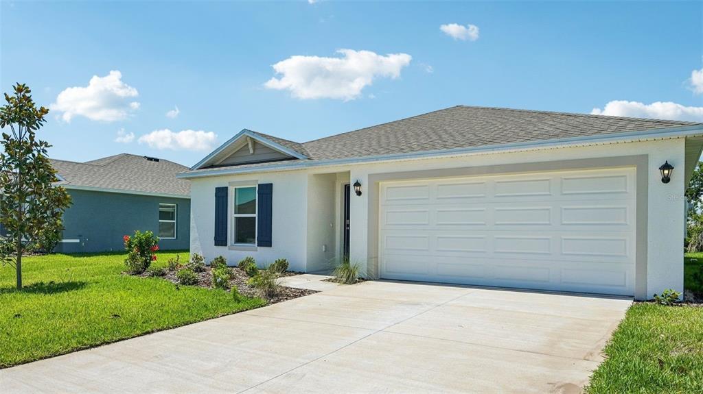 A single-story house with a white stucco exterior, a two-car garage, and a concrete driveway — 10919 44TH AVENUE E, PALMETTO, FL