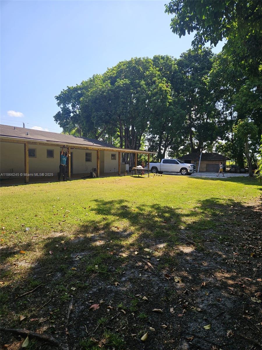 A white house with a covered patio stands on a large, grassy lot with trees — 19230 SW 216TH ST, Miami FL 33170, MIAMI, FL