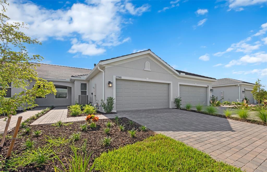 A single-story house with a gray exterior, a three-car garage, and a paved driveway — 27104 CLAM SHELL COURT, ENGLEWOOD, FL