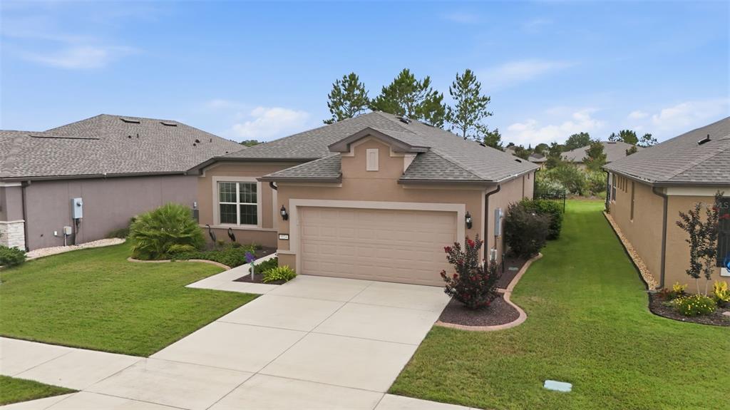 A tan single-story house with a two-car garage and a gray shingled roof — 9534 SW 65TH PLACE, OCALA, FL
