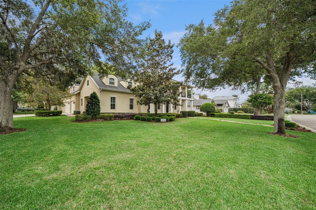 A two-story house with a beige exterior and a large front lawn under trees — 450 LAKEWOOD DRIVE, WINTER PARK, FL