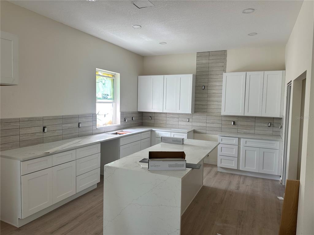 A modern kitchen features white cabinets, quartz countertops, a center island, and gray tile backsplash — 2144 5TH AVENUE N, ST PETERSBURG, FL