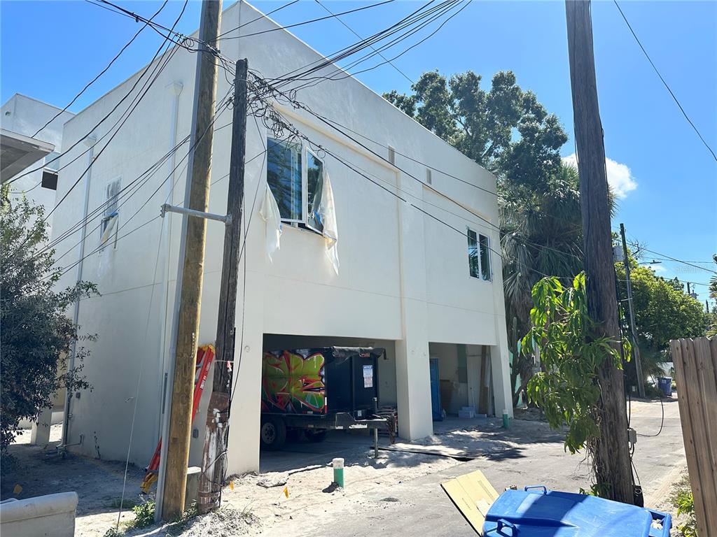 A two-story white building with an open ground-level garage and a graffiti-covered dumpster — 2144 5TH AVENUE N, ST PETERSBURG, FL