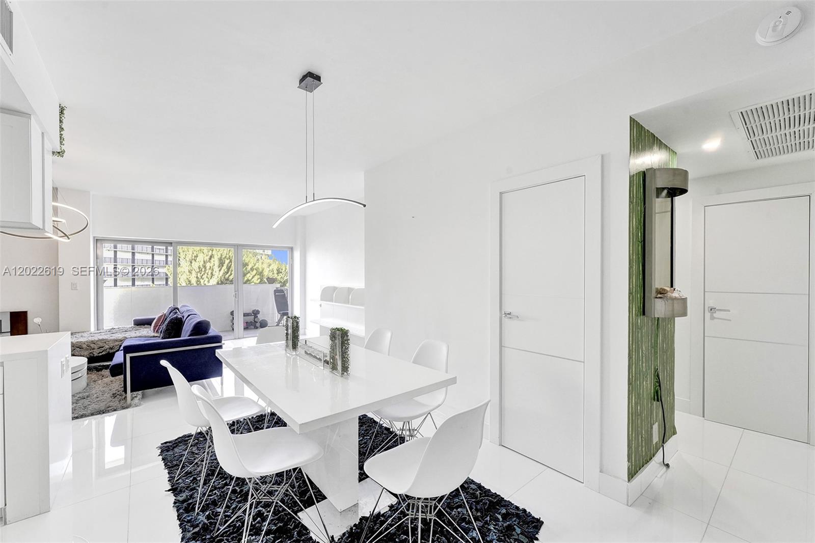 A modern dining area features a white table, chairs, and a dark rug on tile floors — 880 NE 69th St # 5G, Miami FL 33138, MIAMI, FL