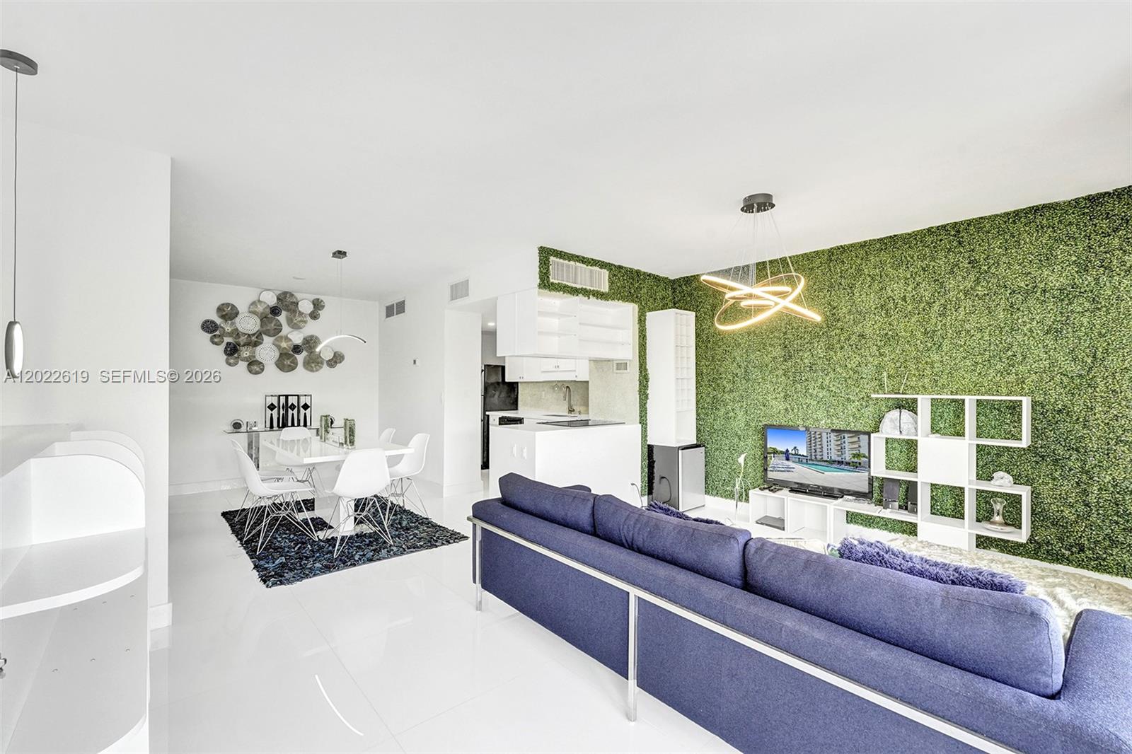A living and dining area features a green wall, blue sofa, and white tile floors — 880 NE 69th St # 5G, Miami FL 33138, MIAMI, FL
