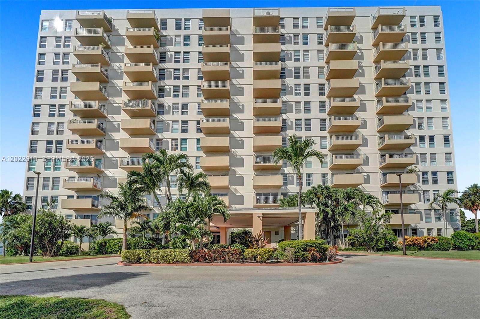 A multi-story residential apartment building features numerous balconies and a ground-level entrance with palm trees — 880 NE 69th St # 5G, Miami FL 33138, MIAMI, FL
