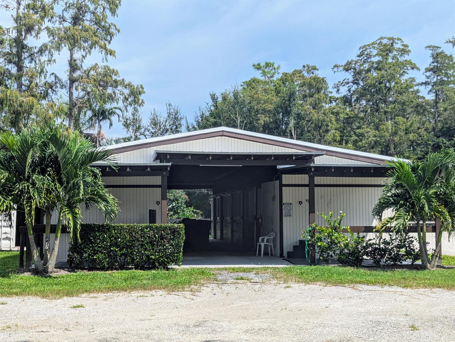 A white barn with a central breezeway, dark trim, and palm trees in the foreground — 13161 Casey Road, FL 33470, FL