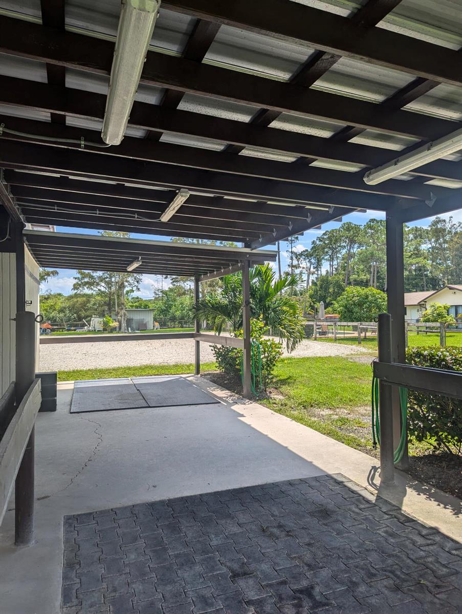 A covered outdoor wash rack with concrete flooring, rubber mats, and a wooden pergola roof — 13161 Casey Road, FL 33470, FL