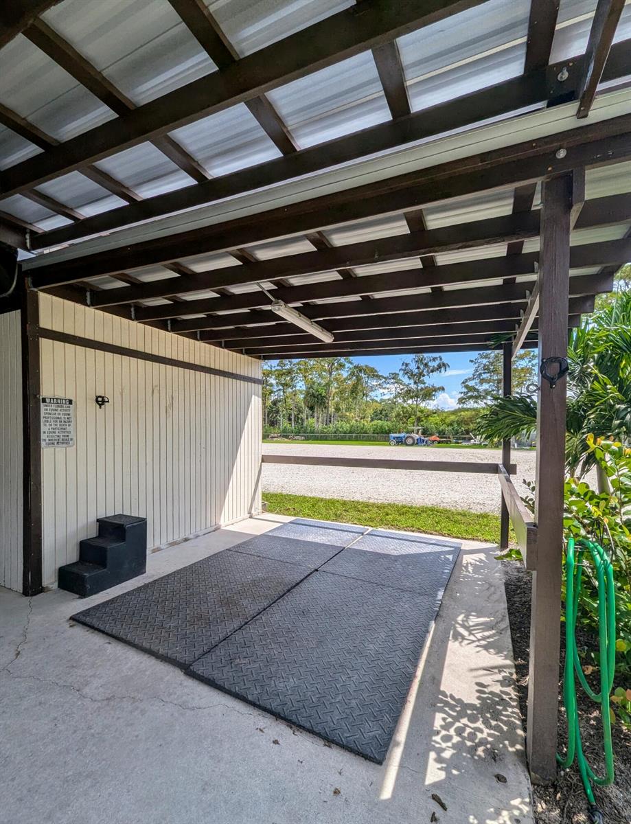An outdoor horse grooming stall with rubber floor mats, a mounting block, and a metal roof — 13161 Casey Road, FL 33470, FL