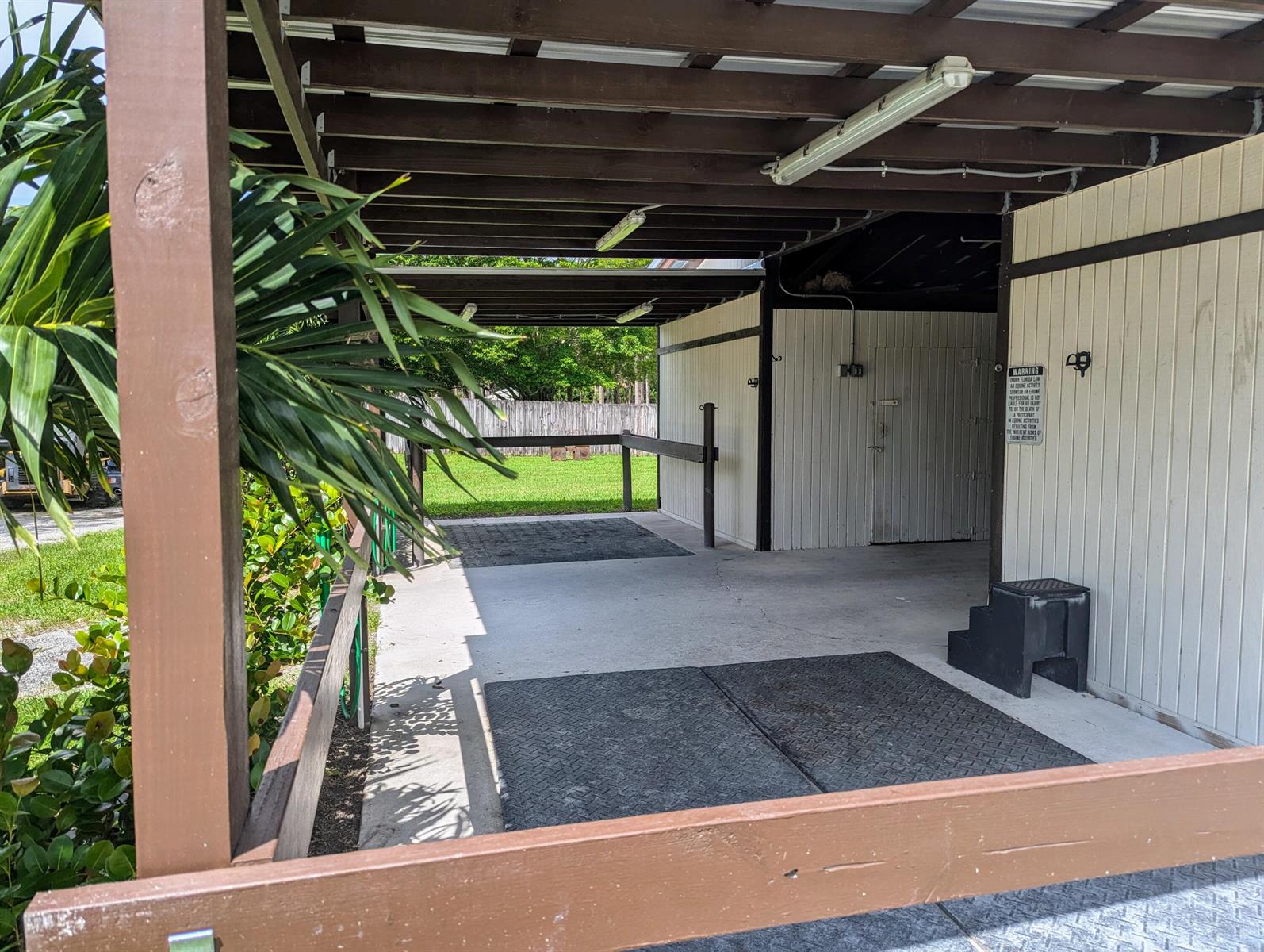 An outdoor covered horse grooming or wash stall area with concrete flooring and rubber mats — 13161 Casey Road, FL 33470, FL